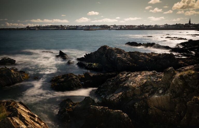 Captivating seascape of Bangor rocks and sea during daytime with a panoramic view of the town.