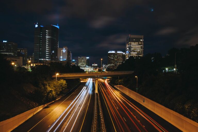 Dynamic night view of an urban highway with light trails and illuminated skyscrapers.
