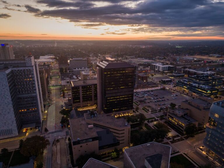 Aerial shot of Rochester, Minnesota skyline during twilight with city lights and sunset colors.