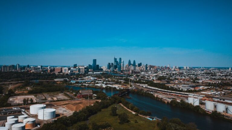 Aerial view of cityscape with modern multistage houses near river with bridge under colorful sky