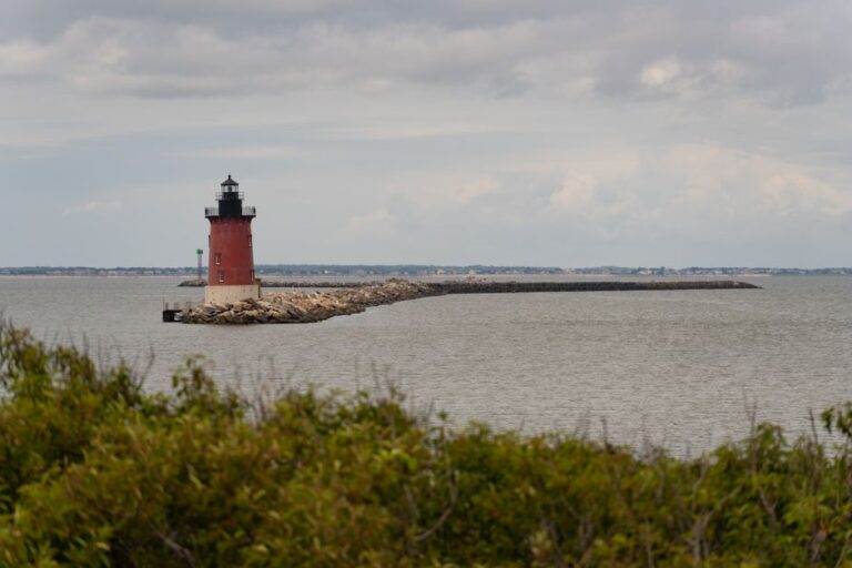 Scenic view of Breakwater Lighthouse in Lewes, Delaware, with dramatic cloudy sky over the sea.