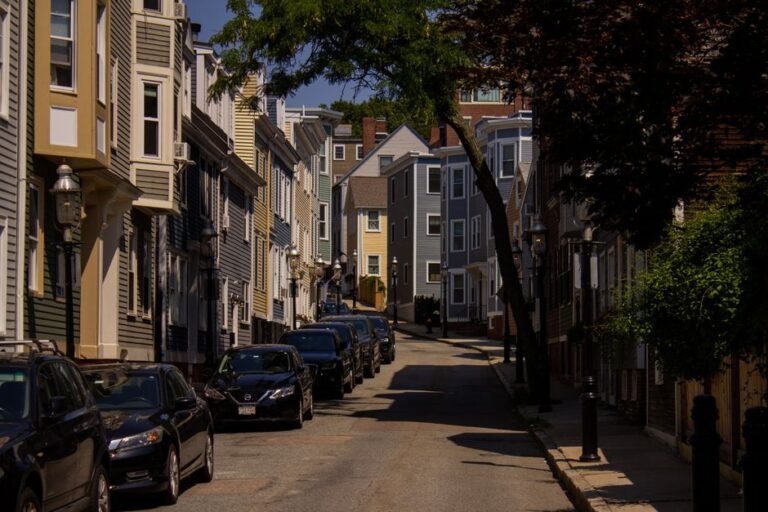 Discover charming Boston streets with parked cars, colorful houses, and lush greenery.