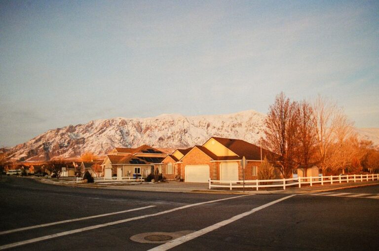 A peaceful suburban street with houses and mountain backdrop at sunrise in winter.